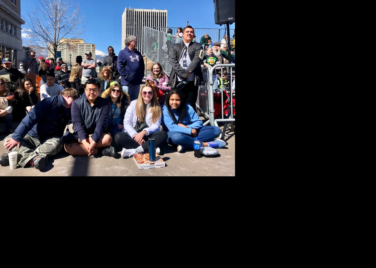 Students sitting on road while waiting for Saint Patricks Day Parade