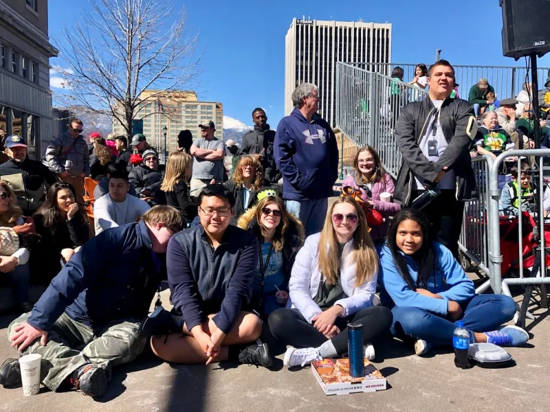 Students sitting on road while waiting for Saint Patricks Day Parade