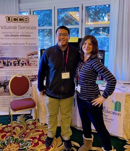 Two students standing in front of a UCCS Inclusive Services banner